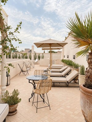 An outdoor patio with a table and chairs, lounge chairs, and a large umbrella.