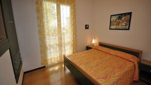 Una camera da letto con un letto, un comodino, una lampada, un quadro appeso e una finestra con tende.