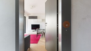 A modern interior with a dining area, a TV, and a door with a number plate. - GuestHost - Modern apartment with balcony in Portello district (Milano)