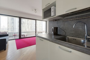A modern kitchen with a large window, a red rug, and a view of the city.