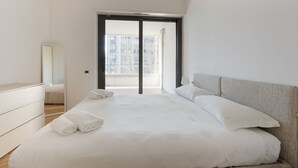 A modern bedroom with a large bed, a dresser, a mirror, and a sliding glass door leading to a balcony. - GuestHost - Modern apartment with balcony in Portello district (Milano)