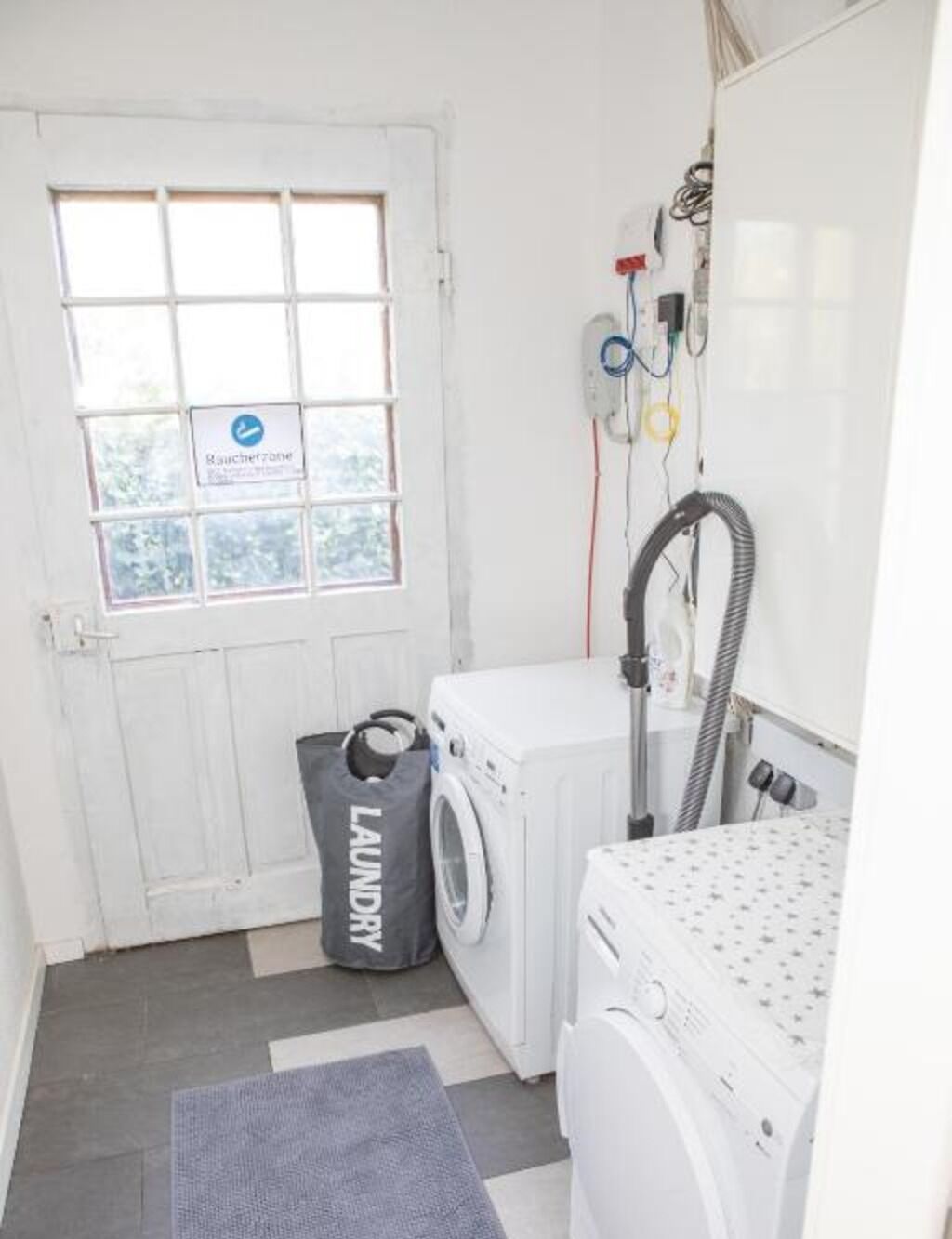 A laundry room with a washing machine, dryer, and a vacuum cleaner.