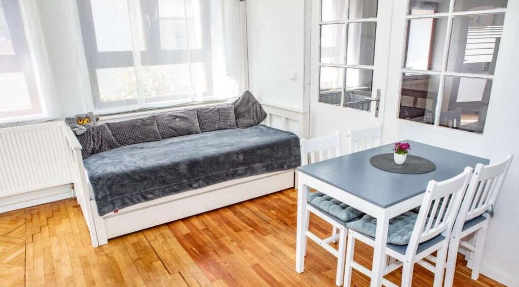 A room with a built-in bench, a table with chairs, and large windows.