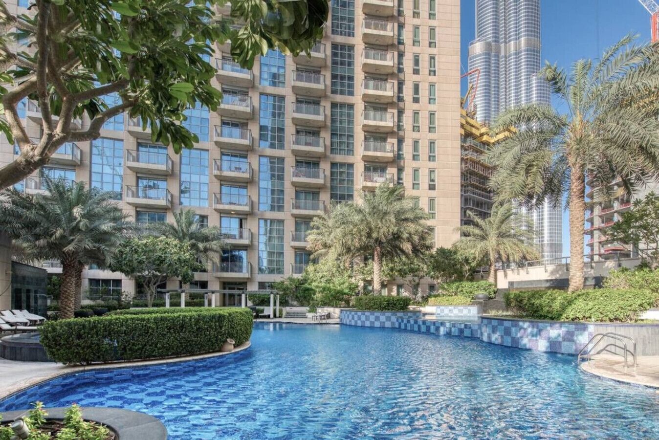 A swimming pool surrounded by lush greenery and tall buildings.