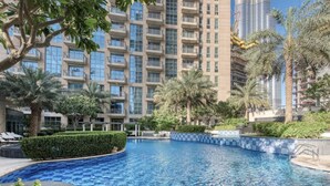 Una piscina circondata da vegetazione rigogliosa e alti edifici.