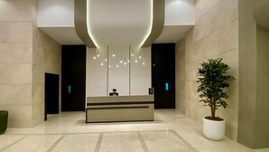 Un'area reception moderna con una scrivania centrale, illuminazione a incasso e una pianta in vaso.