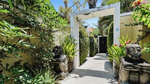 A garden pathway with statues and lush greenery. - Sombra Villa by Kozystay - Sanur (Denpasar)