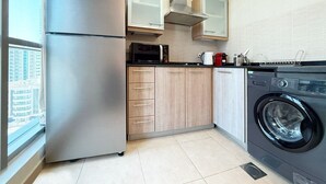 Une cuisine compacte équipée d’un réfrigérateur, d’un four à micro-ondes, d’un four et d’un lave-linge.