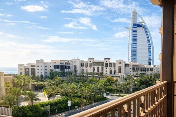 A coastal hotel with a prominent sail-shaped building, palm trees, and a clear sky.