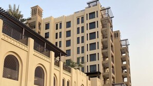 Un hotel de varios pisos con fachada color beige, ventanas grandes y una entrada cubierta.