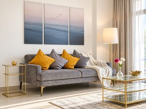 A modern living room with a grey sofa, gold accents, and a glass coffee table.
