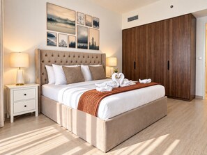 A bedroom with a large bed, two bedside tables, a wardrobe, and artwork on the wall.