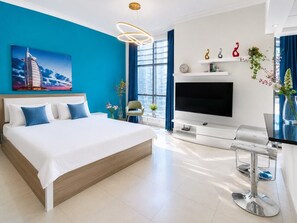 Une chambre d’hôtel moderne dotée d’un grand lit, d’un téléviseur à écran plat, d’un bureau avec une chaise et d’une fenêtre avec des rideaux bleus.
