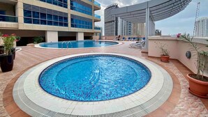 A rooftop swimming pool with a tiled edge and a surrounding patio area. - Cozy Studio at Marina near Beach & Metro in Marina (Dubai)