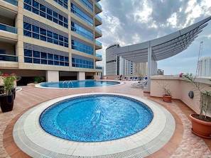 A rooftop swimming pool with a tiled edge and a surrounding patio area.