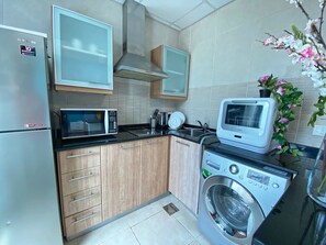 A compact kitchen with a microwave, toaster, and washing machine.