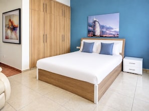 Un dormitorio moderno con una cama grande, un armario de madera, una mesita de noche y un cuadro colgado en la pared.