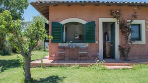 A rustic building with a patio, green shutters, and a small table with chairs. - Tenuta San Calogero App Rosmarino (Sicilia)