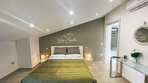 A modern bedroom with a bed, bedside tables, a mirror, and a wall-mounted sign. - Vista Majella by Interhome (Paglieta)