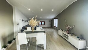 A modern living room with a dining area, featuring a white sofa set, a dining table with chairs, and a vase with flowers. - Vista Majella by Interhome (Paglieta)