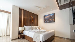 A modern hotel room with a large bed, a nightstand, a wall-mounted air conditioning unit, and a painting of a cityscape.