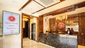 A hotel reception area with a marble reception desk, a clock, and a welcome sign.