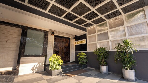 A building entrance with a checkered floor, a dark wooden door, and a sign that reads "Kanalan."