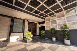 A building entrance with a checkered floor, a dark wooden door, and a sign that reads "Kanalan."