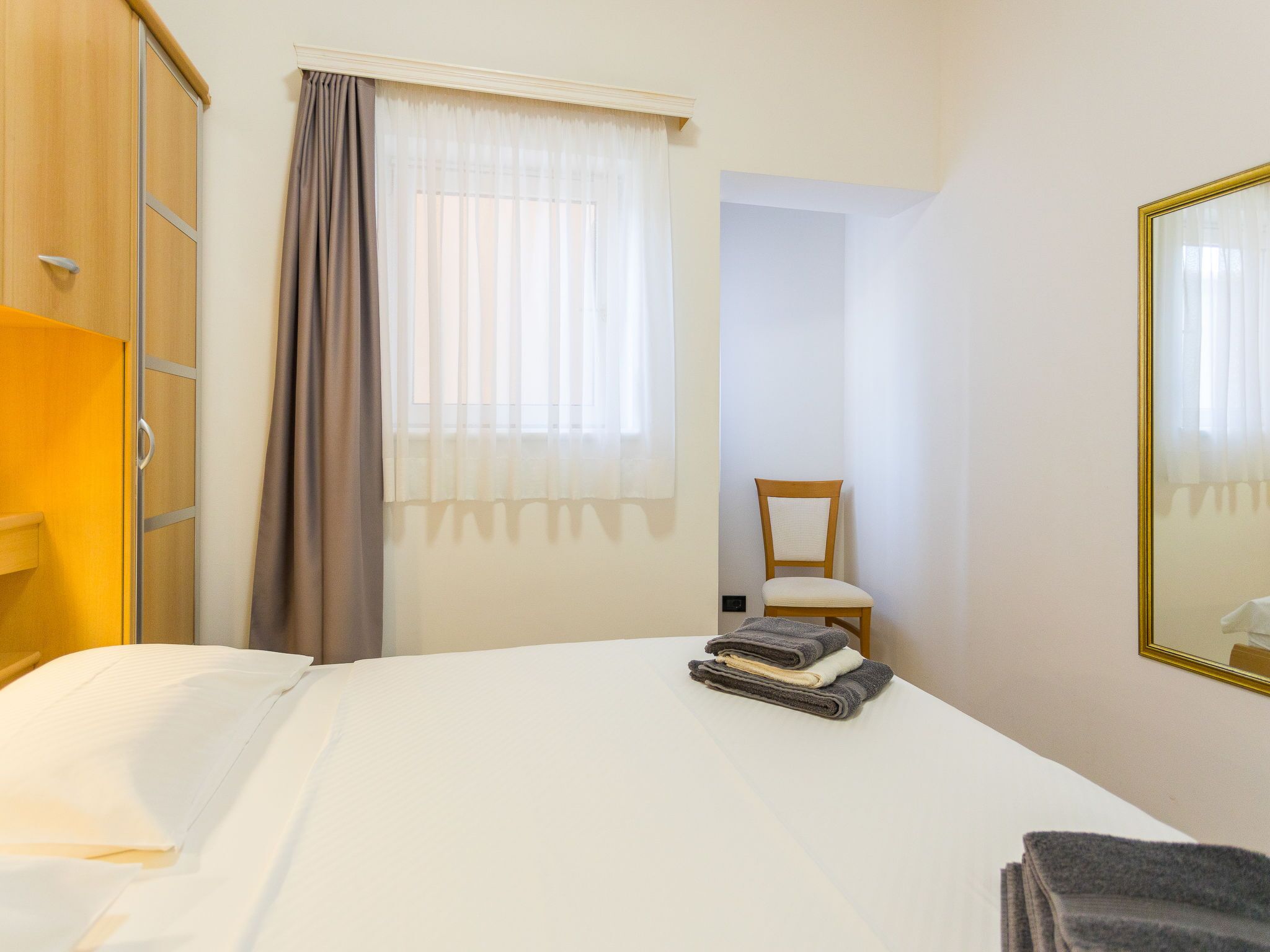 Ein Hotelzimmer mit Bett, Stuhl, Kleiderschrank und Spiegel.
