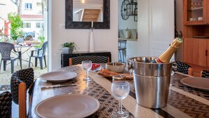 Un coin repas avec une table dressée pour deux personnes, un verre à vin, une bouteille de champagne et un seau en métal.