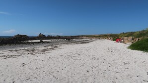 A sandy beach with scattered rocks and a clear blue sky. - Ty Stella by Interhome (Porspoder)