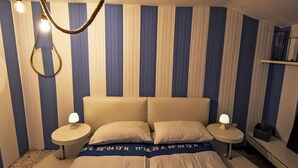 A bedroom with a striped wall, a bed with a headboard, two bedside tables with lamps, and a hanging light fixture. - La Casa di Lu' by Interhome (Chioggia)