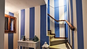 A staircase with blue and white striped walls, a wooden handrail, and a small table with a lamp and a decorative item. - La Casa di Lu' by Interhome (Chioggia)