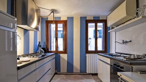 A narrow kitchen with a gas stove, a sink, and a window. - La Casa di Lu' by Interhome (Chioggia)