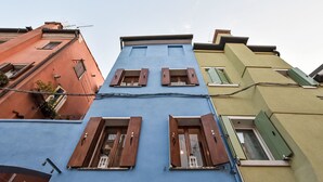 A multi-story building with distinctively colored facades, featuring a central blue section with wooden shutters and a green section on the right. - La Casa di Lu' by Interhome (Chioggia)
