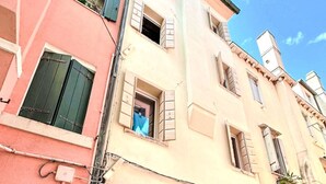 A multi-story building with a pink facade, a beige lower section, and a visible entrance. - La Casa di Cri' by Interhome (Chioggia)