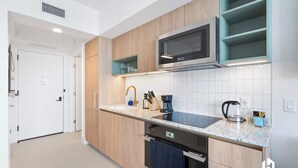 A modern kitchen with wooden cabinets, a microwave, a coffee maker, and a dishwasher.