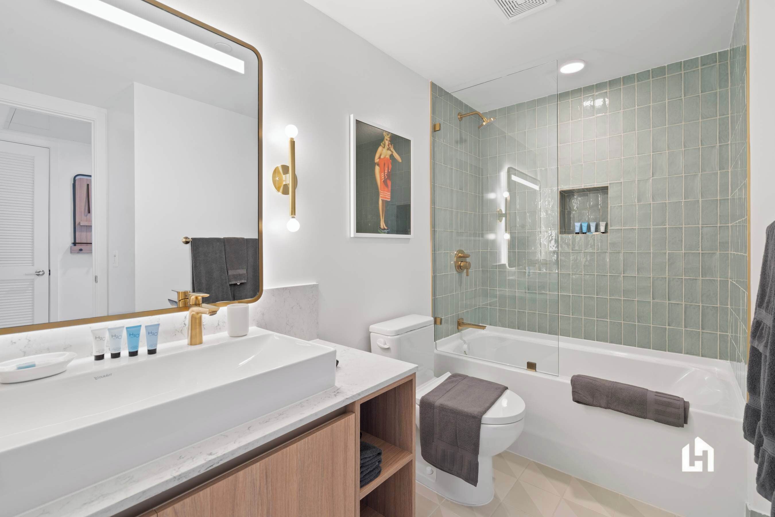 Ein modernes Badezimmer mit großem Spiegel, weißem Waschbecken und einer Badewanne.