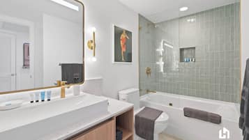 Ein modernes Badezimmer mit großem Spiegel, weißem Waschbecken und einer Badewanne.