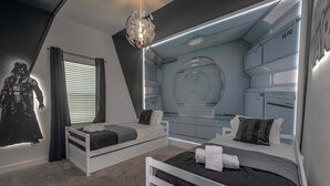 Ein Schlafzimmer mit zwei Betten, einer Wand im Star-Wars-Design und einem futuristischen Stil.