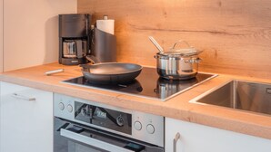 A modern kitchen with a coffee maker, a frying pan, a pot, and a built-in oven. - "Experience unforgettable days in the Dangaster Düne!" (Dangast)