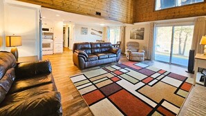 A spacious living area with a leather sofa, a patterned rug, and a view through large windows to the outdoors. - 228 Lakeland (Anderson)