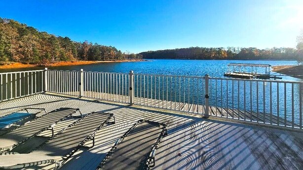 A deck with sun loungers overlooking a lake, a dock, and a forested hillside. - 228 Lakeland (Anderson)