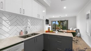 Una cocina moderna con salpicadero de baldosas en espiga, una isla central con fruta y un área de comedor con vistas.