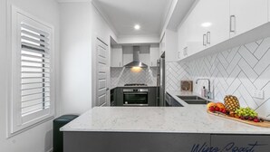 Una cocina moderna con encimera de mármol, salpicadero de baldosas en espiga y horno empotrado.