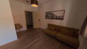 A living room with a sofa, a small table, and a door leading to another room. - 7 Rooms (Losone)