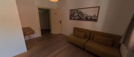 A living room with a sofa, a small table, and a door leading to another room.