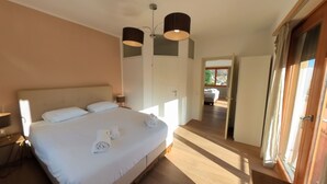 A bedroom with a large bed, two bedside lamps, a wardrobe, and a view of the balcony. - 7 Rooms (Losone)