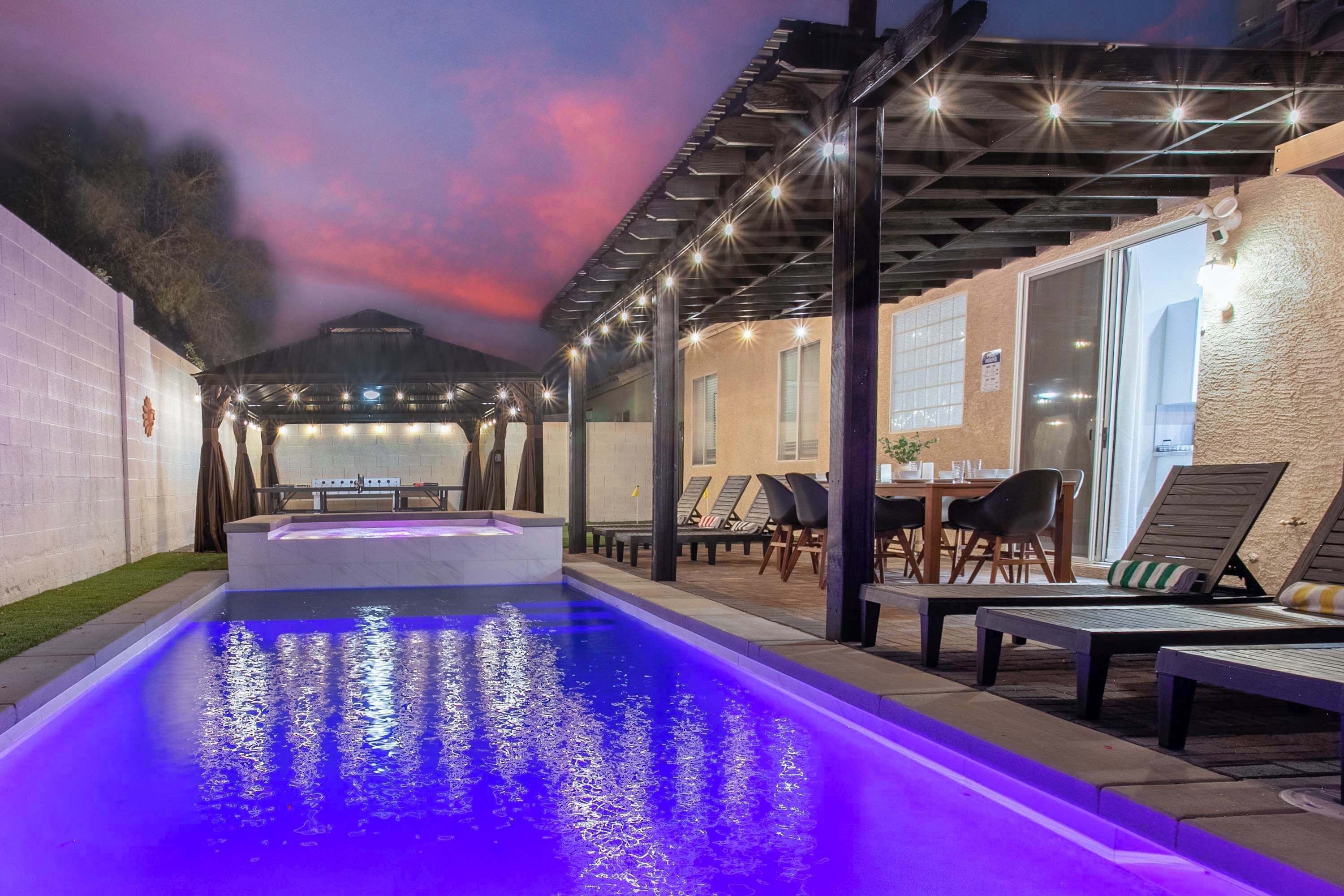 A swimming pool with a water feature, surrounded by lounge chairs and a covered patio area.