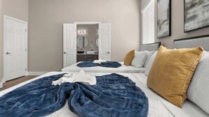 Une chambre avec deux lits, une armoire et une salle de bain visible à travers une porte ouverte.